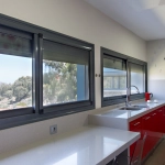 Cuisine moderne avec comptoir blanc et placards rouges.