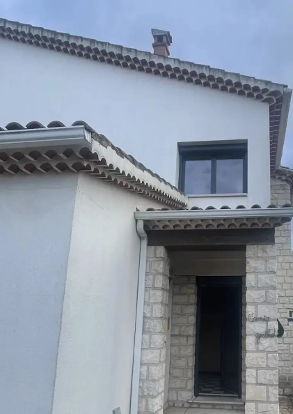 Entrée de maison en pierre avec fenêtres modernes.