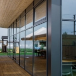 Terrasse en bois avec grandes fenêtres vitrées modernes.